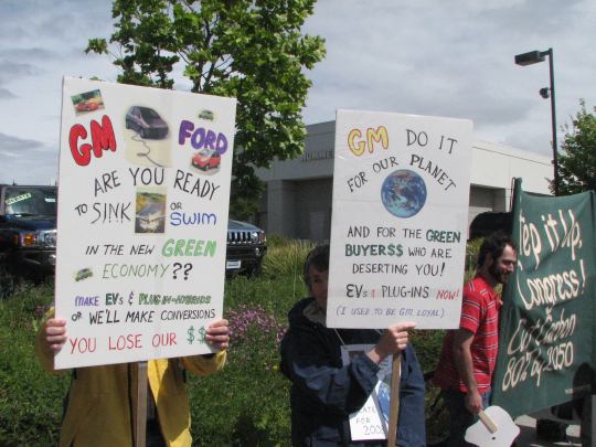 Two protesters holding posters in front of San Rafael's GM/Hummer dealership, April, 2007
